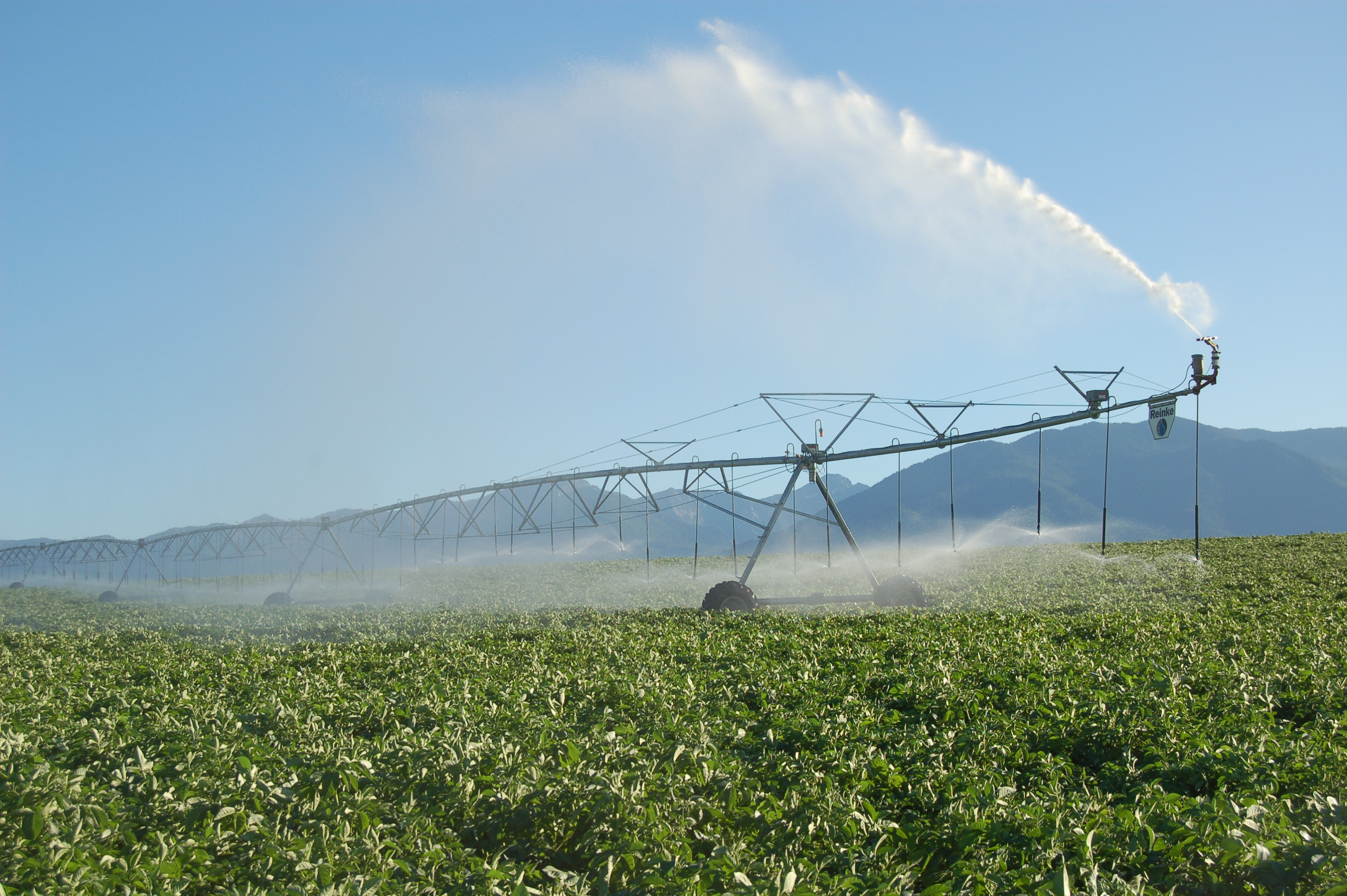 Reinke pivot running above a field with mountains in the background.